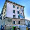 An old building with some old art and an old ger in front