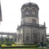 The spire, or tower, at the top of the castle, surrounded by lush gardens