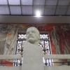 A very large bust of Lenin in the entrance, with a mural behind him