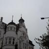 A magpie perched on a distant rooftop spire