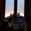 A pale sunset illuminating the rooftops and church steeples as seen through a kitchen window
