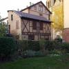 A timber-framed house standing in the back garden of a larger house