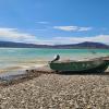 A boat on the shore of a blue reservoir we stopped at to wash all the mud off our boots during a break in the storm