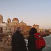 A couple looks at the historical sites one evening in Cádiz