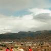 Here is the view from a mirador overlooking the city of Cusco, featuring three ladies in traditional dress and an alpaca