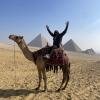 This picture shows a fun camera trick! The camera is close to me on the camel, but the pyramids are far away. Things close to the camera look bigger, and things that are far away look small, so it looks like I am taller than the pyramids.