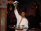 Waiter in a traditional Moroccan restaurant pouring the tea 