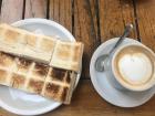 A delicious "cafe con leche" or coffee with milk along with sandwiches with ham and cheese. 
