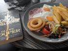 Eating ham, eggs, and chips (or fries) and reading a book across from the beach 