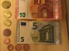 A few small bills and coins of euro currency (€).