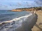 The coves are made up of a mixture of rocks and sand. You can see scuba divers preparing to dive on a rock in the distance.