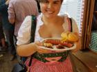 Dressed in a traditional Austrian dress eating a käsekrainer