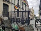 La Paz's police officers stand underneath both the indigenous peoples' flag and the Bolivian flag, waiting for marchers to come through 