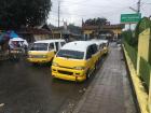 On a quiet afternoon while students are learning, yellow angkots wait to take arriving customers home