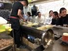 The chef fries the egg before putting it on the okonimiyaki