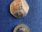 British pounds - the top coin is worth 50 pence (half of a pound), and the bottom coin is worth one pound