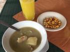 A soup with potatoes and chicken with fresh orange juice and dried corn kernals