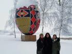 My friends and I standing in front of a giant statue of a painted egg covered in snow