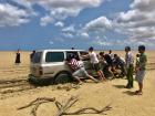 Travelers work together to push the car from the sand in the desert of La Guajira