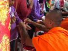 A Khmer monk tying a red string around a young girl's wrist