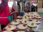 Canteen staff prepare to serve students a traditional plate of white rice and chicken