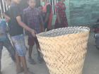 Boys measuring their height against a fish drying basket made from palm leaves