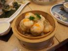 Steamed dumplings filled with cooked shrimp. Broccoli and orange fish eggs on top for decoration.