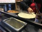 To prepare the crêpe, the chef spreads a thin layer of batter on a hot griddle.