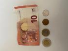 10 euro bill and euro coins alongside a USA dime for size reference