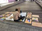 A man draws portraits with crayon.