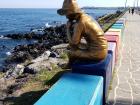 A fisherman statue on the colorful coast of Jeju Island