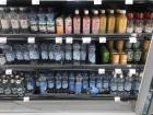 A grocery store's water aisle, with varying prices and options including coconut water