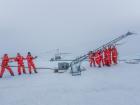 A team of scientists raise the MET Tower, a 10-meter tall instrument that measures atmospheric properties at different heights