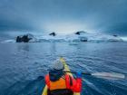 A'aifou kayaking towards snow-capped mountains