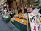 Fresh vegetables and fruits already wrapped in plastic sit outside a small grocery store