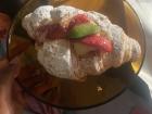 A croissant filled with custard and topped with candied fruit purchased at a local bakery