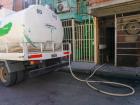 A truck providing water to residents in a villa settlement