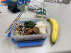 Typical school lunch, with sesame pork and sauteed greens, mushrooms and tofu paired with rice, a banana and a carton of soy milk)