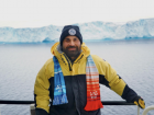 Salvatore in front of the Denman glacier with the climate stripes scarf indicating Earth’s warming since 1961
