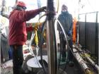 Team members working with the drill head as it descends into the ice (Sarah Bouckoms, IceCube/NSF)
