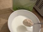 Adding the first spoonful of gofio to a warm bowl of milk
