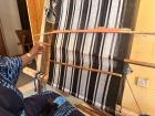 Mrs. Ovavu pulls the black weft thread through the small opening underneath the Okaha. 