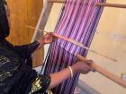 Mrs. Ovavu slides the Okaha all the way through the first layer while still holding the Ochi-aya, before grabbing both ends of the Okaha and beating down the weft.