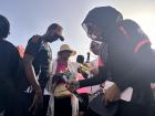 Kids keeping cool with popsicles during a breast cancer awareness walk on a hot day.