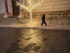 There is a small Christmas tree outside of a church in the piazza.