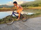 A boy in my neighborhood racing me on his bike next to a rice field