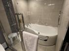 Bathtub and shower behind sliding glass door