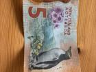 The $5 bill features a cute penguin