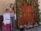 My host cousin and I posing next to their decorated door! She is in traditional dress and there are examples of typical regional foods in front of the door.