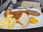 An English breakfast with scrambled eggs, beans, chicken sausage, tomato, fried egg and toast
